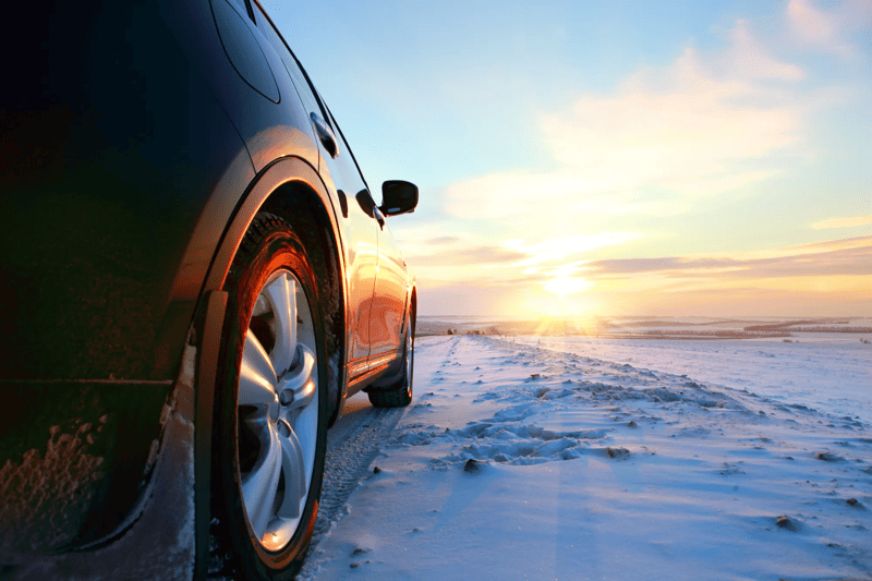 Car on winter road at sunset.