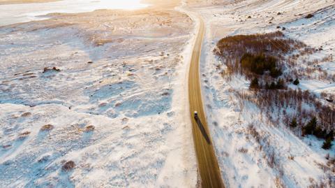 Aerial view of a car driving on road in snow covered winter Iceland